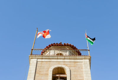 Low angle view of flag on building against clear blue sky