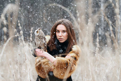 Portrait of beautiful young woman with owl outdoors