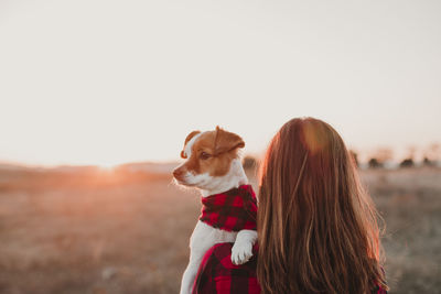 Woman with dog on field against sky during sunset