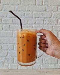 Close-up of hand holding drink on table