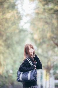 Full length of woman standing against tree