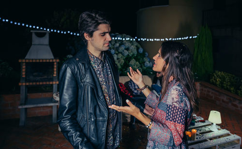 Young friends talking during party in backyard at night