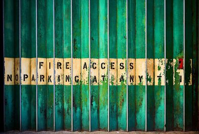 Close-up of text on old metal fence