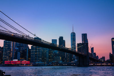 Bridge over river by buildings against sky in city
