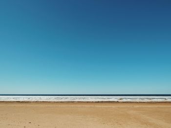 Scenic view of beach against clear blue sky