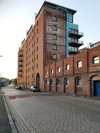 Street by buildings against sky in city