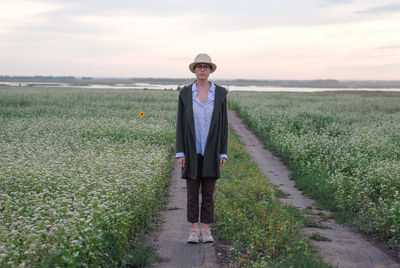 Portrait of man standing on field against sky