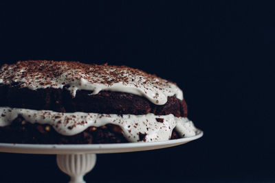 Close-up of chocolate cake on cakestand against black background