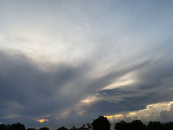 Low angle view of sunlight streaming through clouds