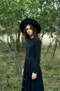 Young woman standing against trees