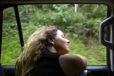Young woman leaning out car window from car interior