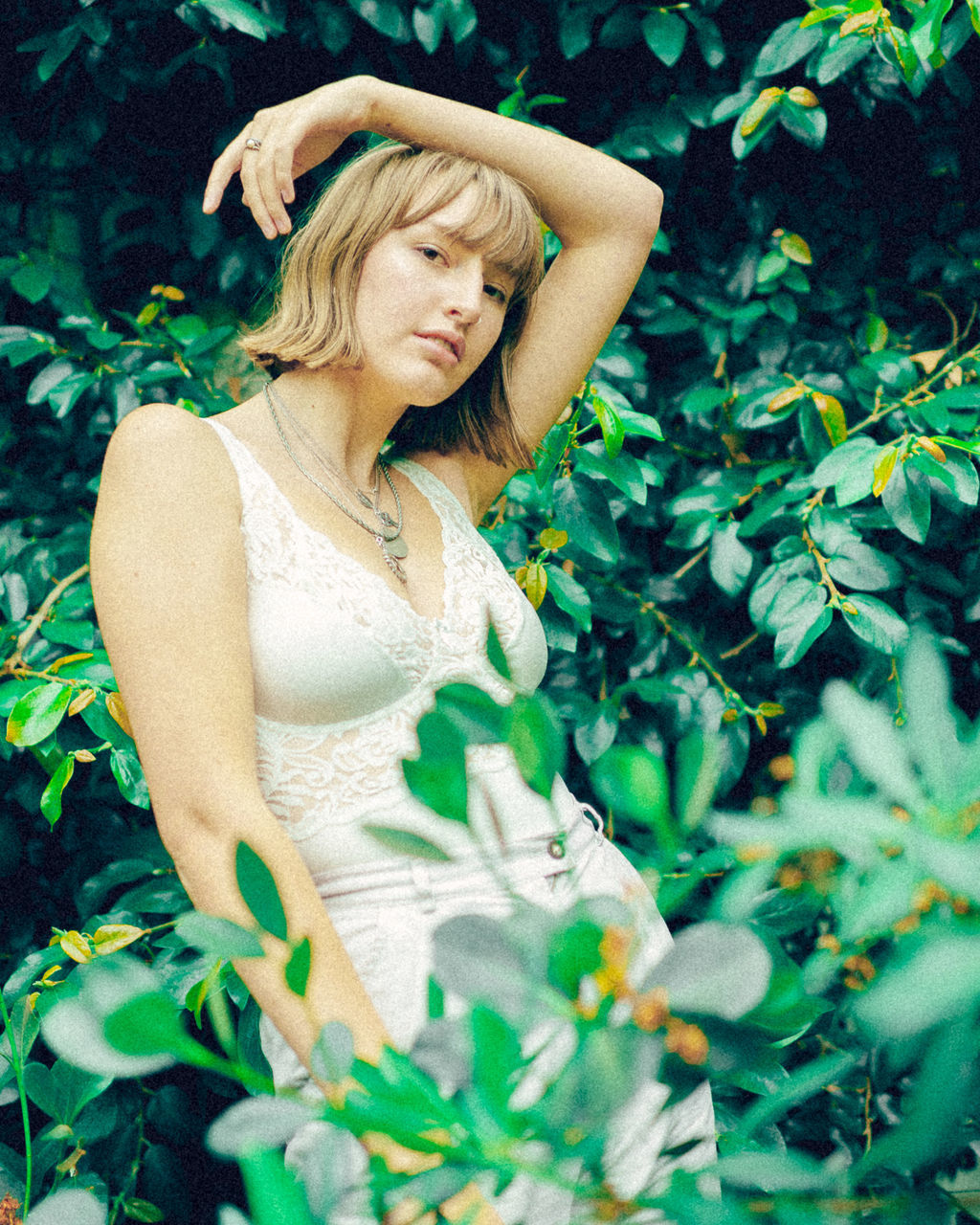 one person, women, beautiful woman, plant, adult, hair, blond hair, beauty, standing, plant part, waist up, leaf, portrait, looking, day, green color, nature, front view, hairstyle, fashion, outdoors, contemplation