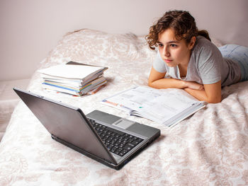 Young woman using mobile phone while sitting on bed