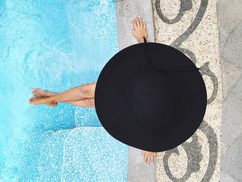 Directly above view of woman with black hat sitting by poolside in ijen suites hotel