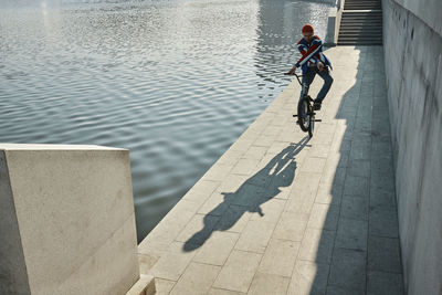 Man doing stunt with bmx bike near lake on embankment