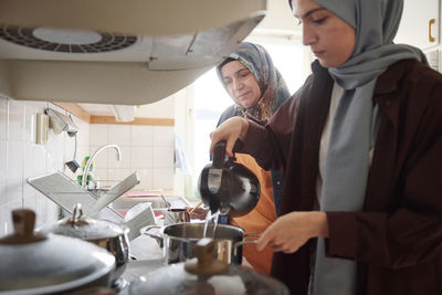 Women in headscarves cooking together for eid al-fitr at home