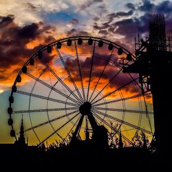 Low angle view of ferris wheel against cloudy sky