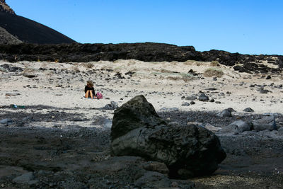 Rear view of person on rock against sky