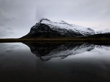 Scenic view of lake by snowcapped mountain against sky