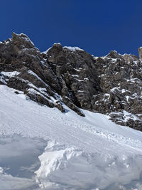 Scenic view of snow covered mountains against clear blue sky