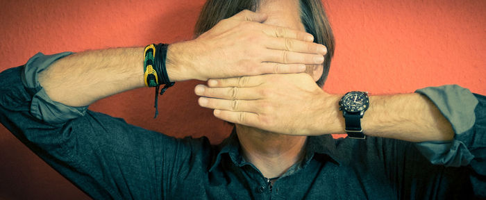 Panoramic view of man covering face with hands against wall