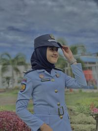 Portrait of smiling young woman standing against waterfall