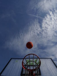 Low angle view of basketball in mid-air over hoop