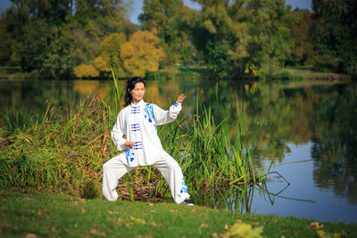 Full length of woman practicing martial arts while standing at lakeshore