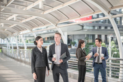 Business people discussing while standing on elevated walkway