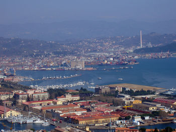 High angle view of illuminated city by sea against sky