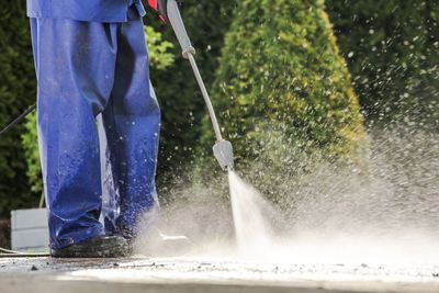 Low section of worker washing footpath