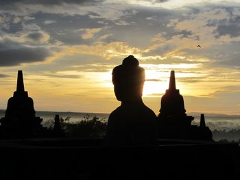 Silhouette statue against sky at sunset