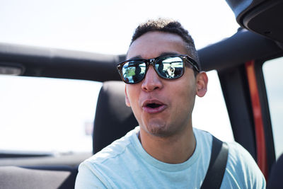Close-up of man wearing sunglasses while traveling in off-road vehicle against sky