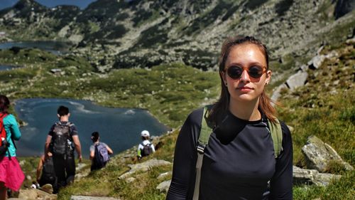 Portrait of young woman wearing sunglasses standing on mountain