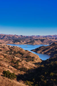 Scenic view of lake and mountains against clear blue sky