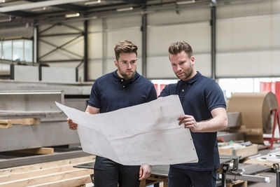 Two men looking at plan in factory