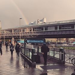 People at railroad station in city against sky