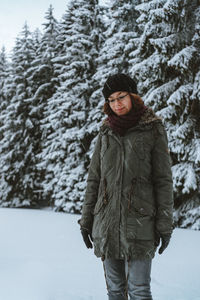 Young woman standing against trees during winter