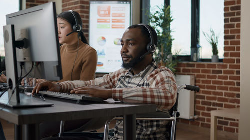 Customer service representative with colleague working at desk in office