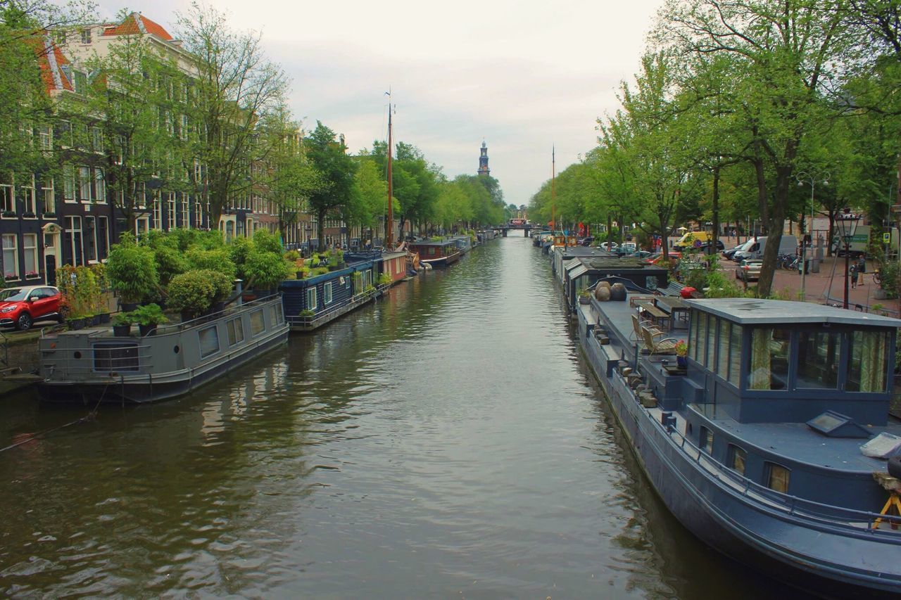 BOATS MOORED IN CANAL AMIDST CITY