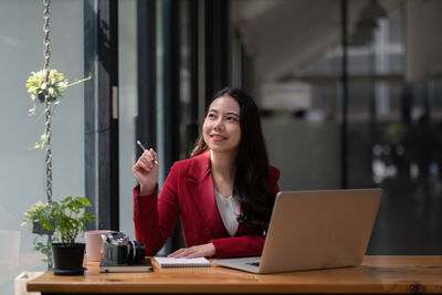 Young woman using phone while sitting on table