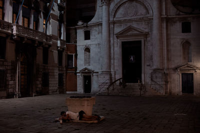 People sitting on street against old building in city