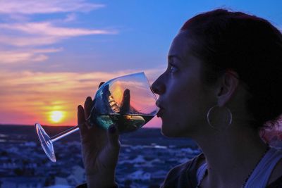 Side view of mid adult woman drinking wine during sunset