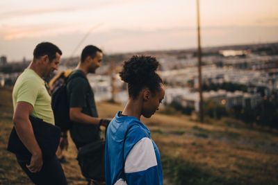 Male and female athletes standing on land during sunset