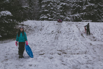 Full length of girls standing on bobsled in snow