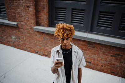 Multiracial guy teenage student using smartphone outdoor on city street