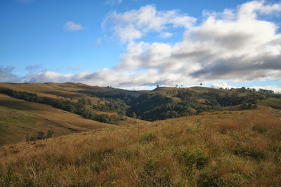 Scenic view of landscape and field against cloudy sky