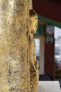 Close-up of gold-covered buddha statue against building