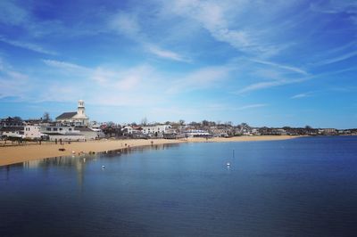 Scenic view of sea by buildings against blue sky