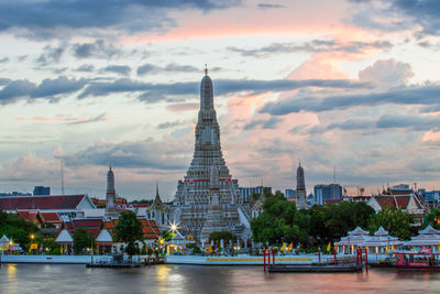 Buildings at waterfront against cloudy sky